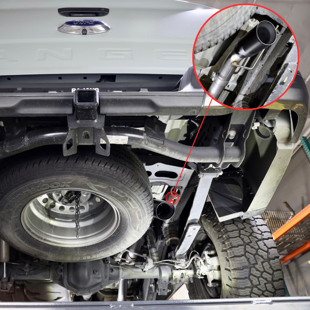The underside of a vehicle with a magnified portion showing a close up of an installed 2019-2023 Ford Ranger Over Axle Carven Exhaust Dump Kit