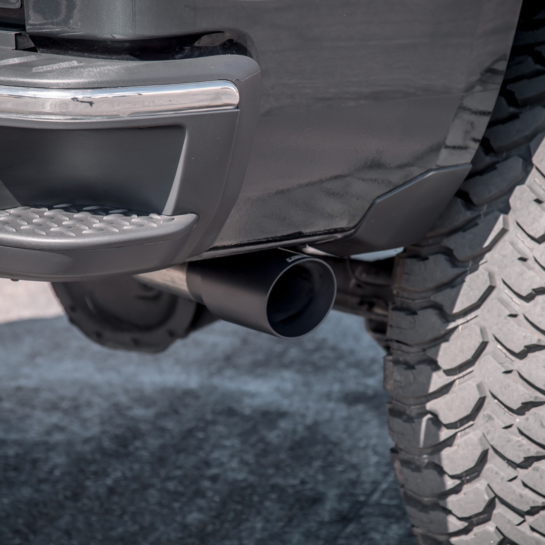 A close up of aCarven Exhaust 4.00" Universal Bolt-On Exhaust Tip in cerakote black color installed on a truck