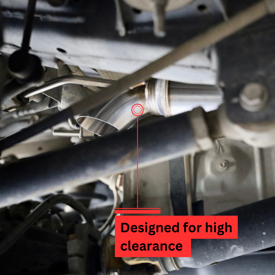 A close up of the installed 2007-2014 Toyota FJ Cruiser Carven Exhaust High Clearance Dump Exit Exhaust System on the underside of a vehicle with text that says "Designed for high clearance"