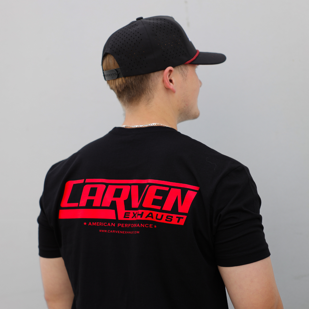 A man modeling a black shirt with a red Carven Exhaust logo on the back