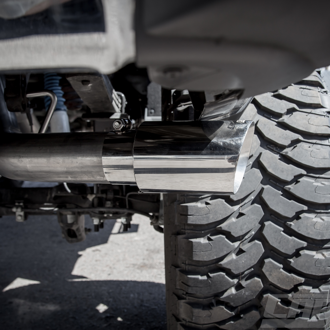 A close up shot of an installed Carven Exhaust 4.00" Universal Bolt-On Exhaust Tip in polish color