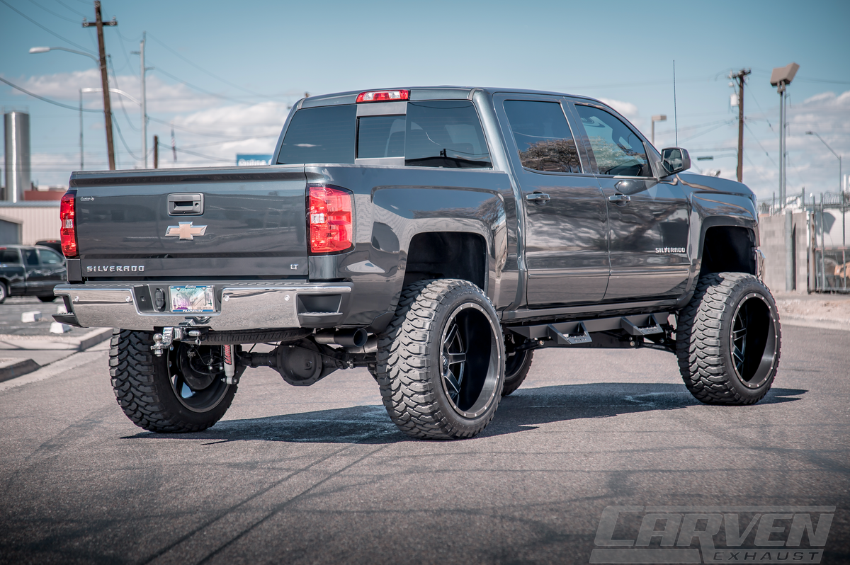 Wide shot of a dark gray Chevrolet Silverado truck with an installed 2010-2018 Chevrolet Silverado & GMC Sierra 1500 Carven Exhaust COMPETITOR Series Cat-Back Exhaust Kit with a cerakote black 4.0” Single Exit Tip