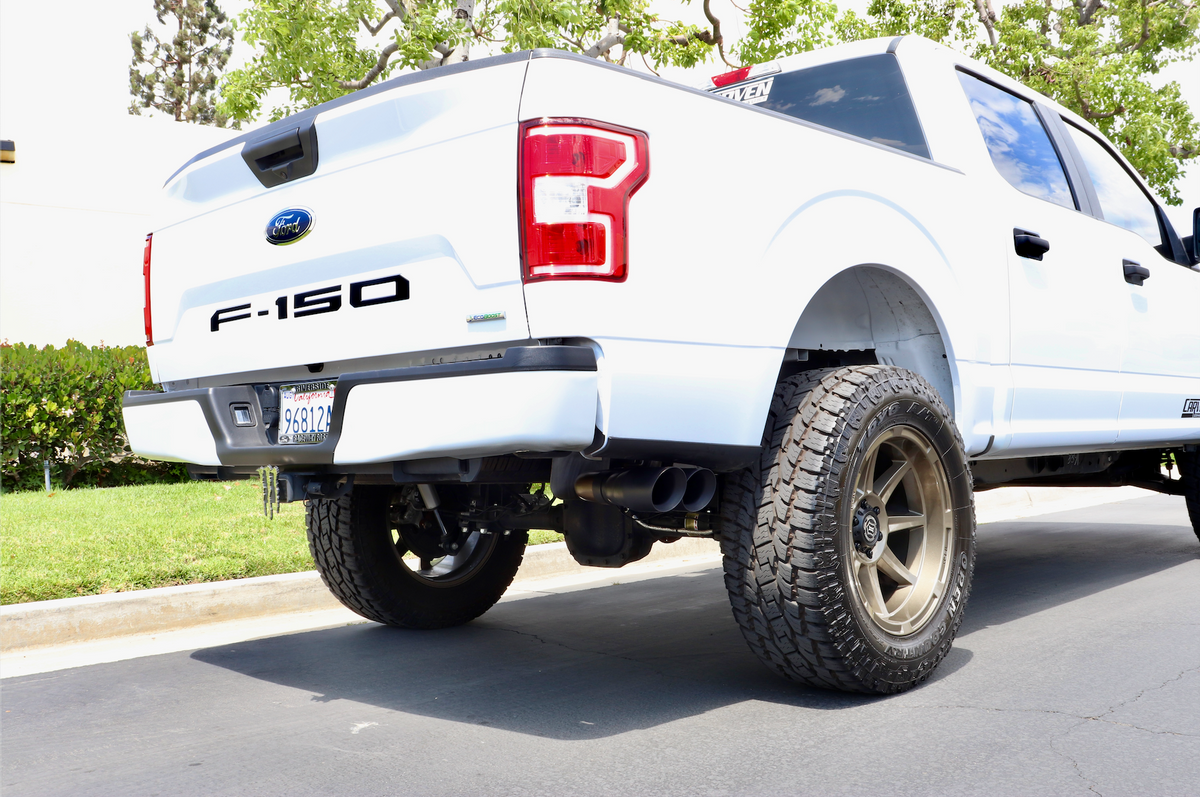 A white Ford F-150 truck with an installed EcoBoost Carven Exhaust Cat-Back Kit with 4” Dual Exit Tips in the Cerakote black color