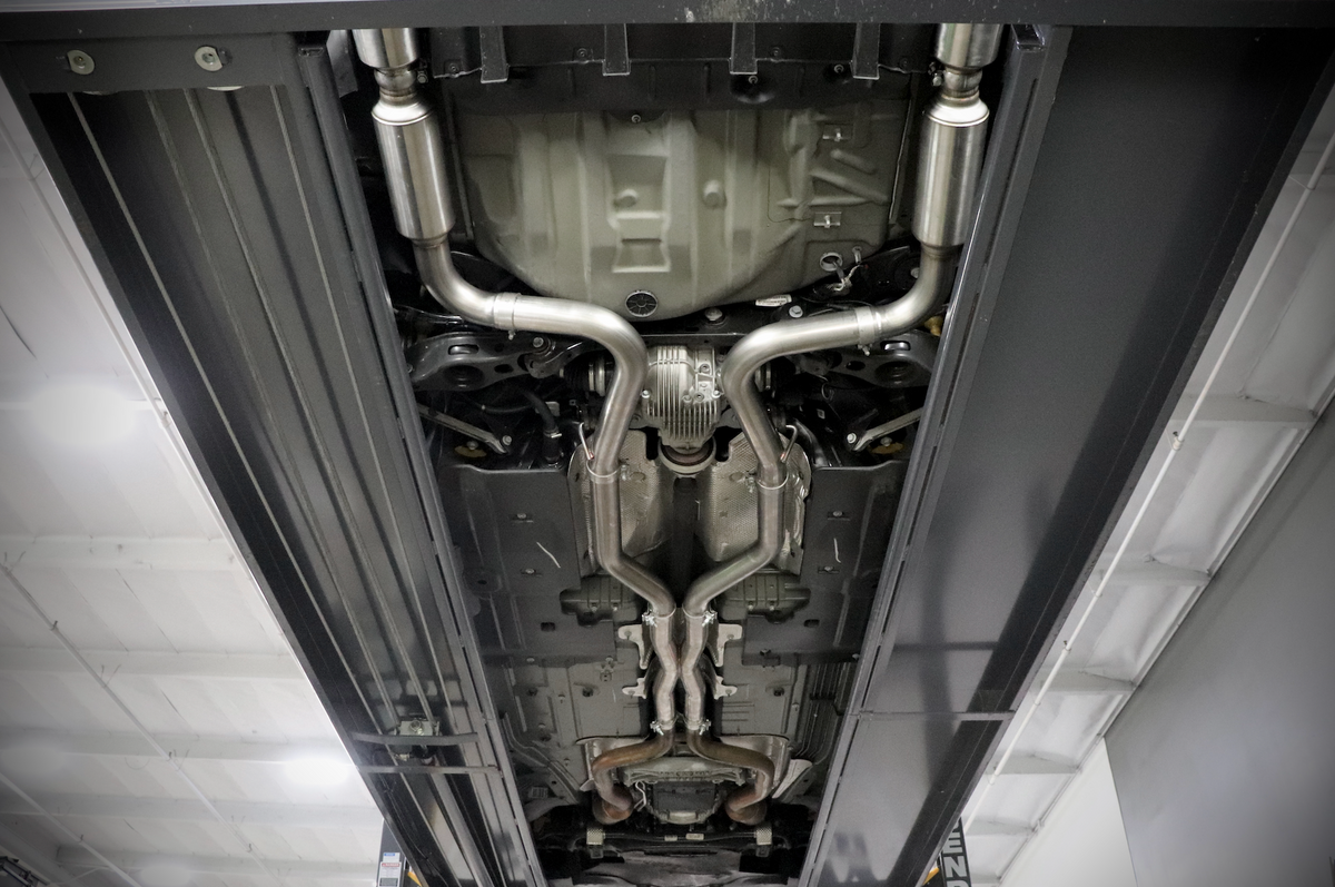 The underside of a vehicle with an installed 2015-2023 Dodge Charger Carven Exhaust Cat-Back Exhaust Kit