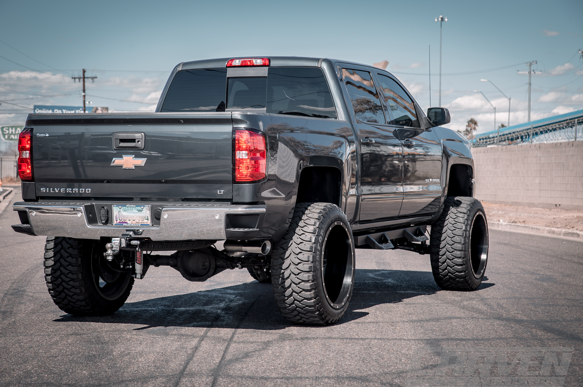 Wide shot of a dark gray Chevrolet Silverado truck with an installed 2010-2018 Silverado & Sierra 1500 Carven Exhaust PROGRESSIVE Series Cat-Back Exhaust Kit with a polished stainless 4.0” Single Exit Tip