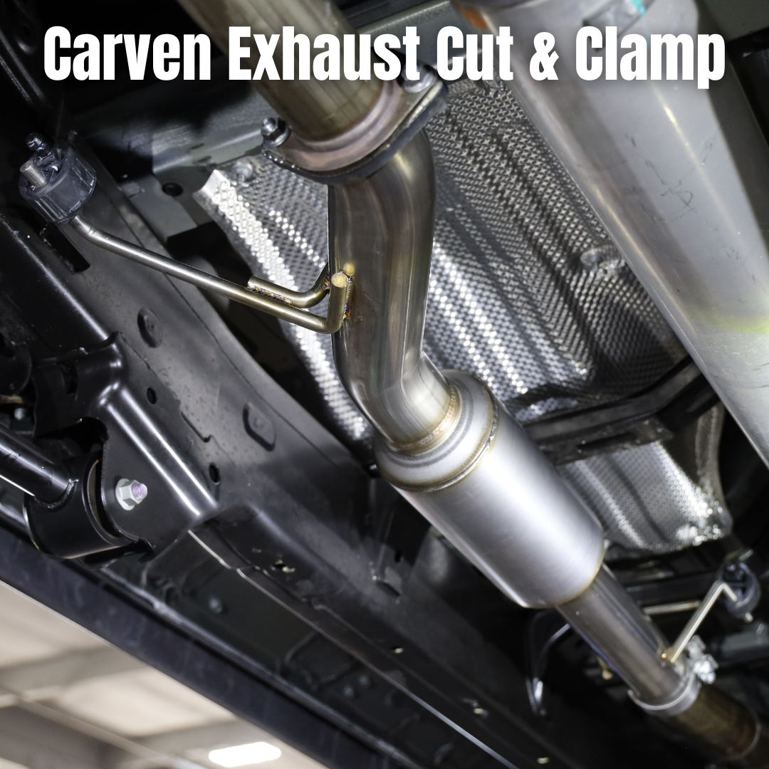 Close up of an installed 2022-2025 Toyota Tundra Carven Exhaust Cut & Clamp Muffler Replacement Kit on the underside of a vehicle with text that says "Carven Exhaust Cut and Clamp"