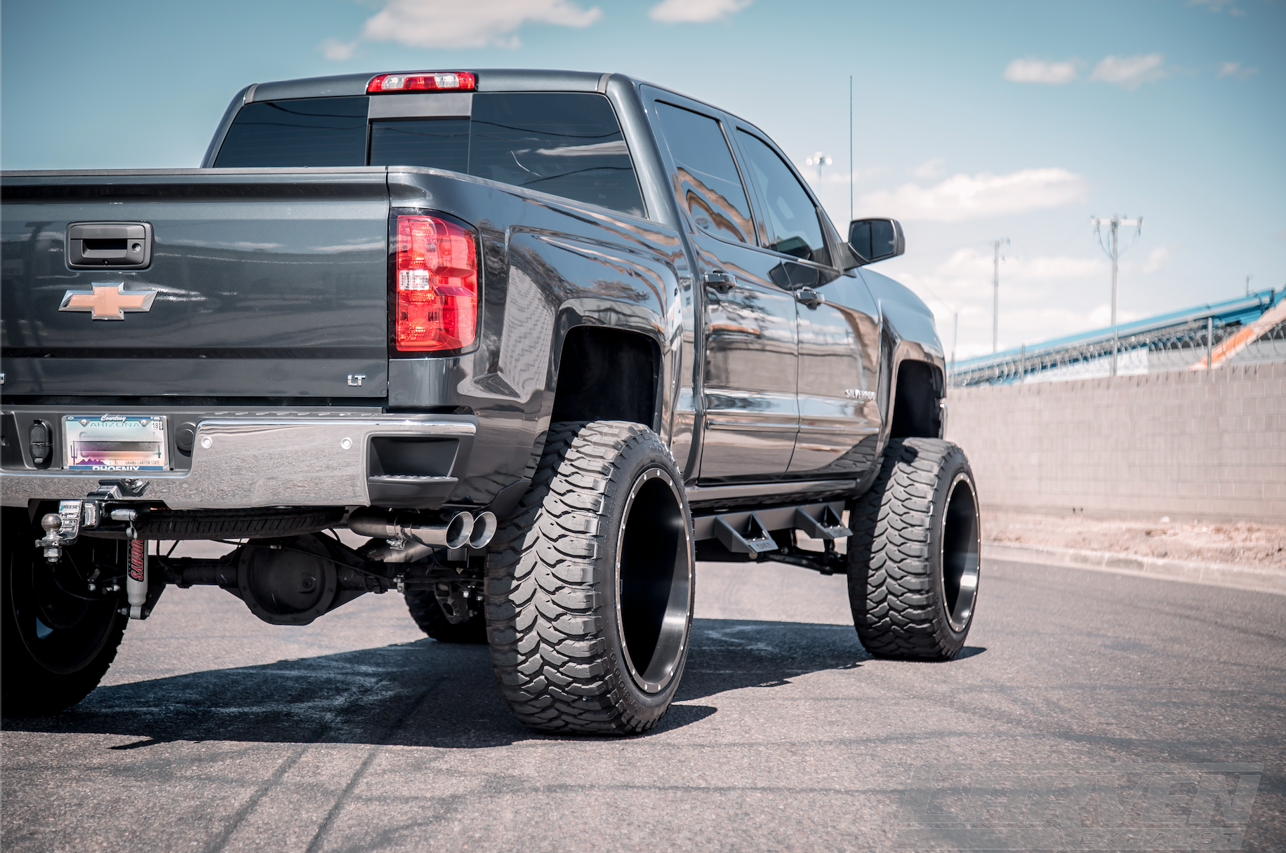 Wide shot of a dark gray Chevy Truck with an installed 2010-2018 Silverado & Sierra 1500 Carven Exhaust PROGRESSIVE Series Cat-Back Exhaust Kit with a Polished stainless 4.0” Dual Exit Stainless Steel Tip