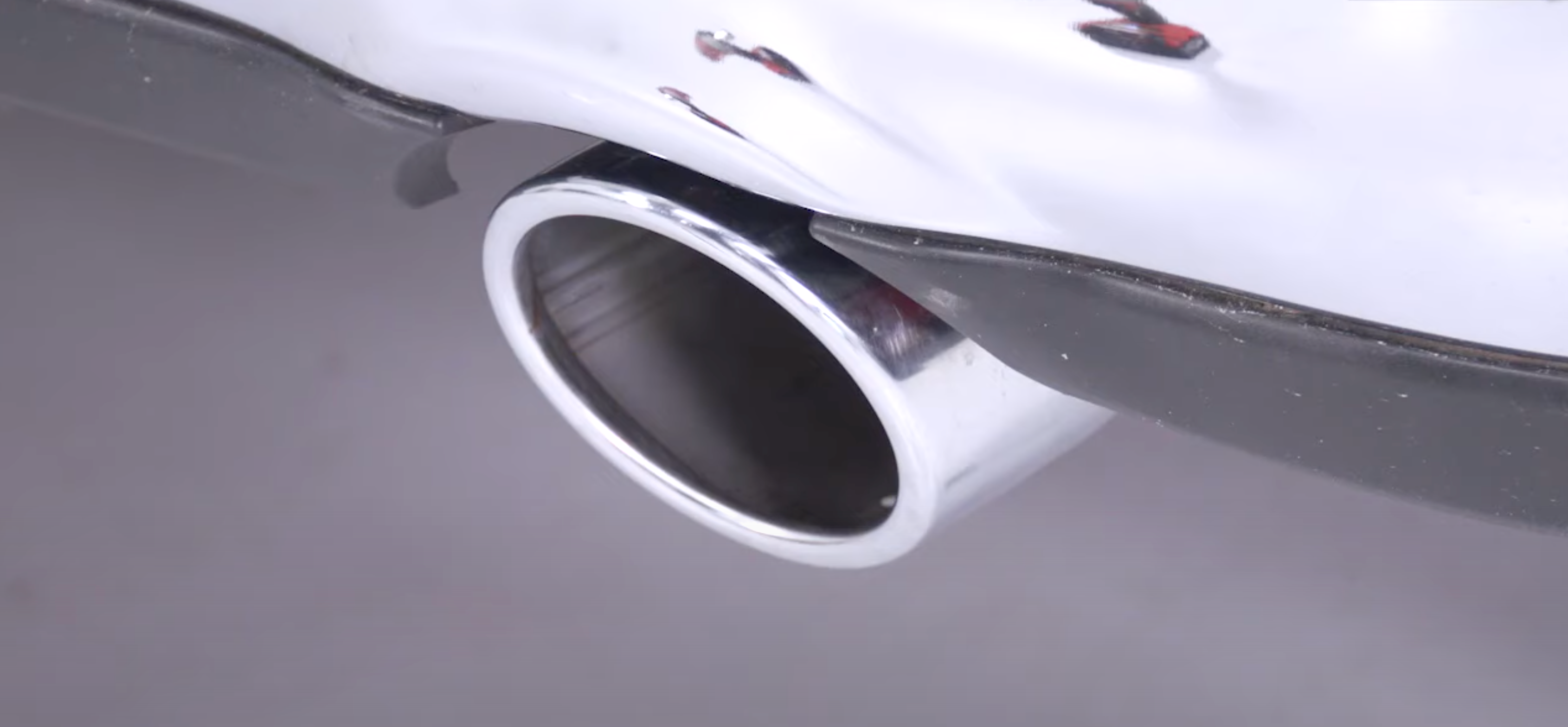 Close up of an installed 2009-2018 RAM 1500 Carven Exhaust 5.0" Direct Fit Bolt-On Exhaust Tip Replacement Set in the polished stainless color on a white vehicle