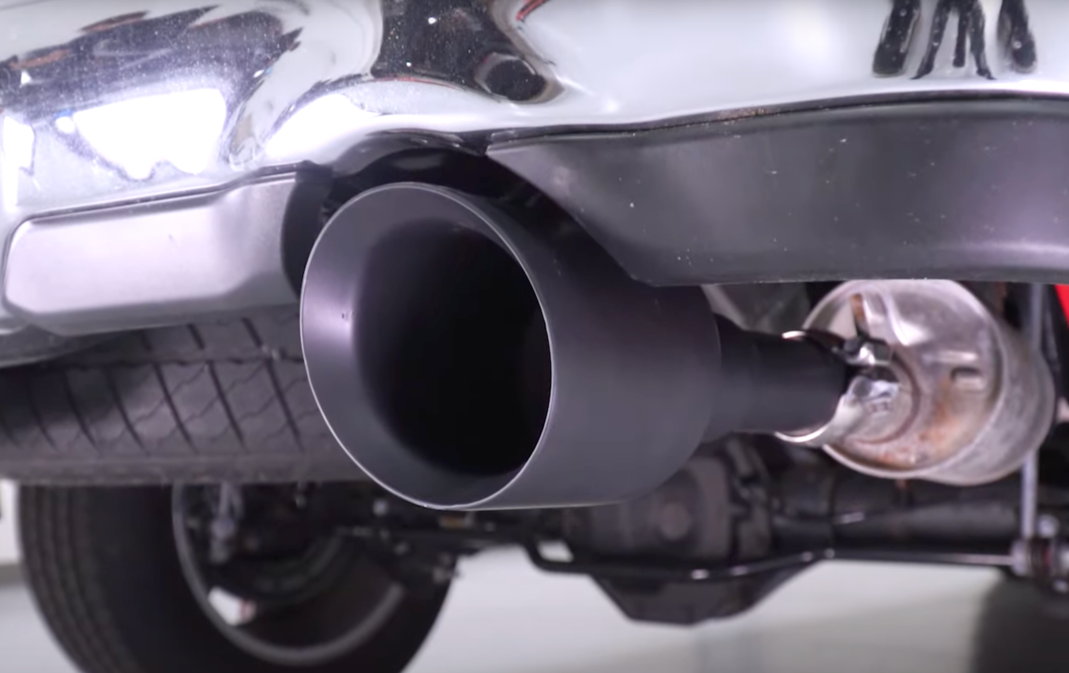 Low-angle close-up of an installed 2009-2018 RAM 1500 Carven Exhaust 5.0" Direct Fit Bolt-On Exhaust Tip Replacement Set in the ceramic coated black color