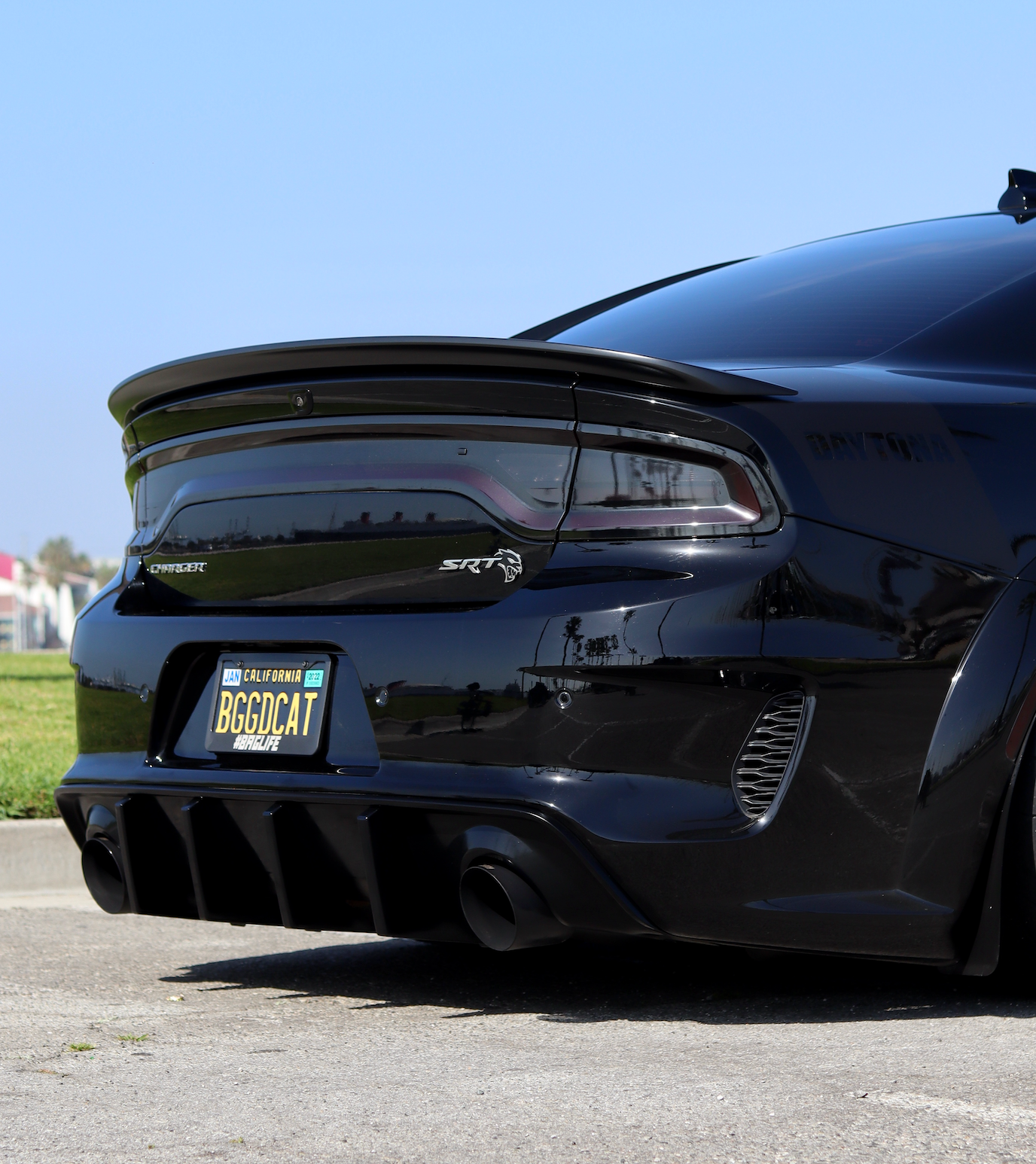 The angled backside of a black Dodge Charger car with an installed 2015-2023 Dodge Charger Carven Exhaust 5.0" Tip Replacement Set