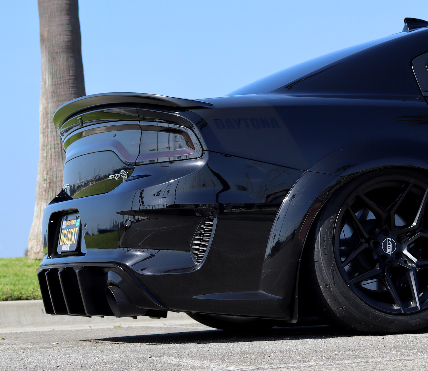 A slightly angled photo of the backside of a Black Dodge Charger car with an installed 2015-2023 Dodge Charger Carven Exhaust 5.0" Tip Replacement Set