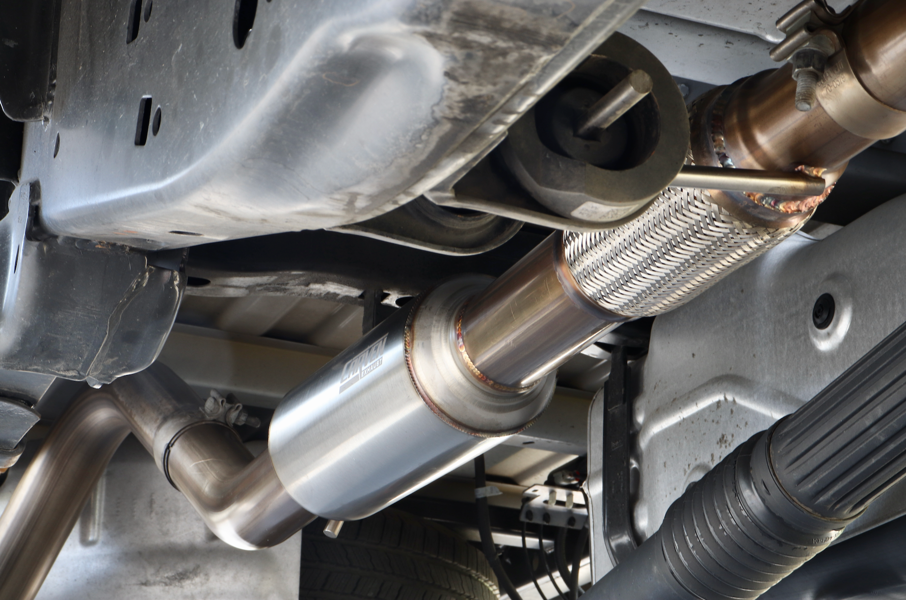 The underside of a vehicle with an installed 2015-2020 Ford F-150 EcoBoost Carven Exhaust Cat-Back Kit