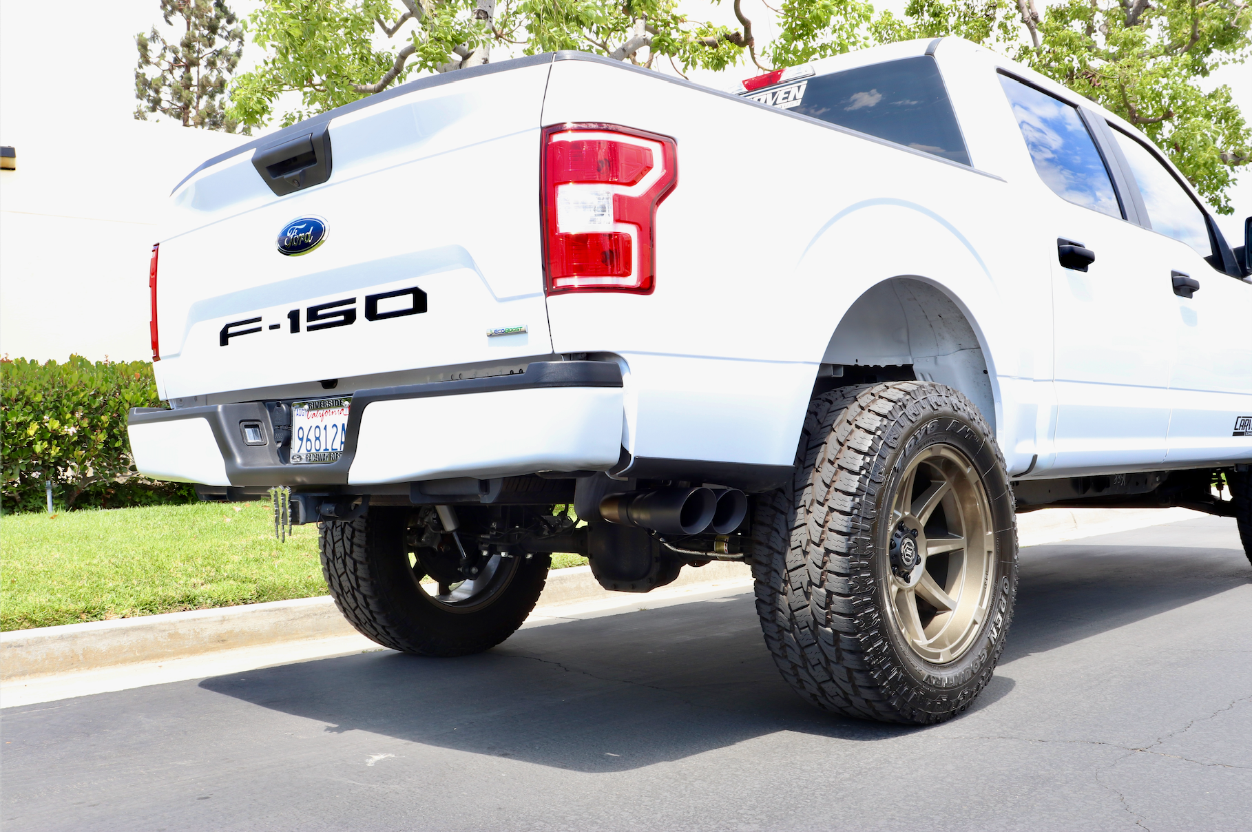 A white Ford F-150 truck with an installed EcoBoost Carven Exhaust Cat-Back Kit with 4” Dual Exit Tips in the Cerakote black color