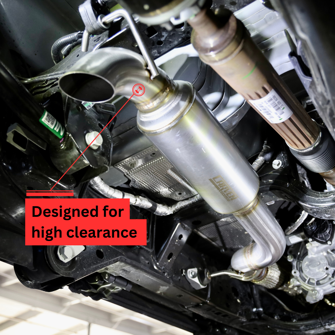 An installed 2021-2025 Ford Bronco 2.7L Carven Exhaust Dump Exit Kit on the underside of a vehicle, with text that says "Designed for high clearance"