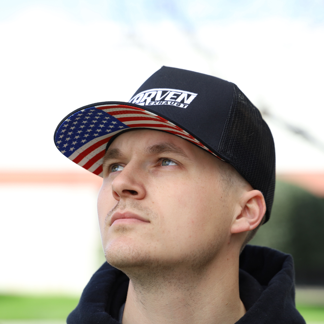 A man wearing a black hat with a white Carven Exhaust logo and an American flag brim
