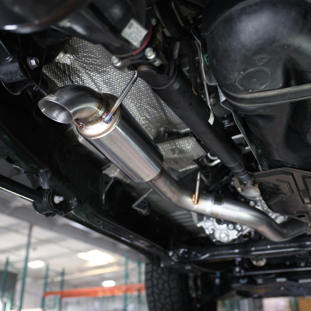The 24-25 Toyota Land Cruiser Carven Exhaust Dump Exit Kit installed on the underside of a vehicle