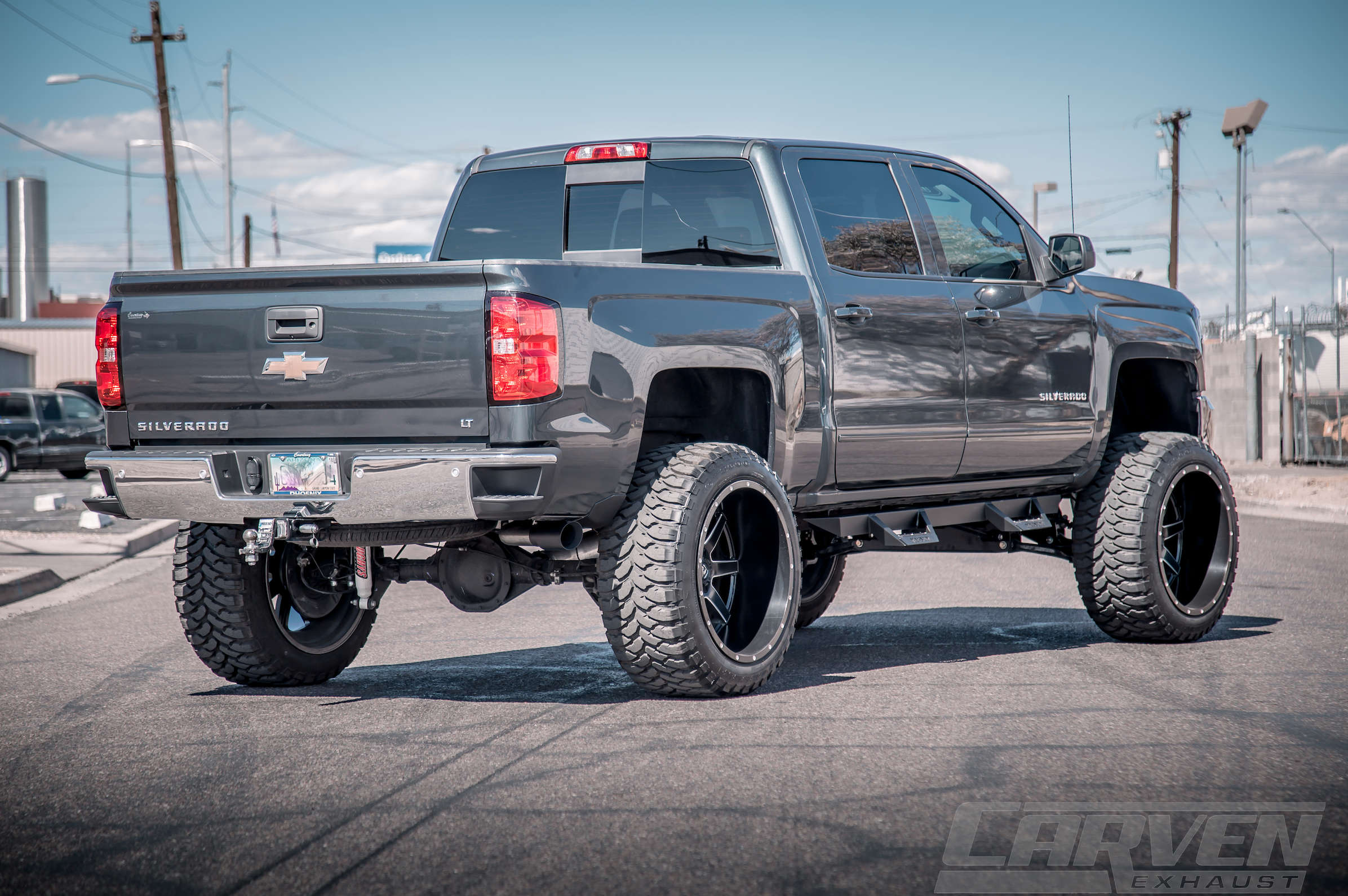 Wide shot of a dark gray Chevrolet Silverado truck with an installed 2010-2018 Silverado & Sierra 1500 Carven Exhaust PROGRESSIVE Series Cat-Back Exhaust Kit with a cerakote black 4.0” Single Exit Tip