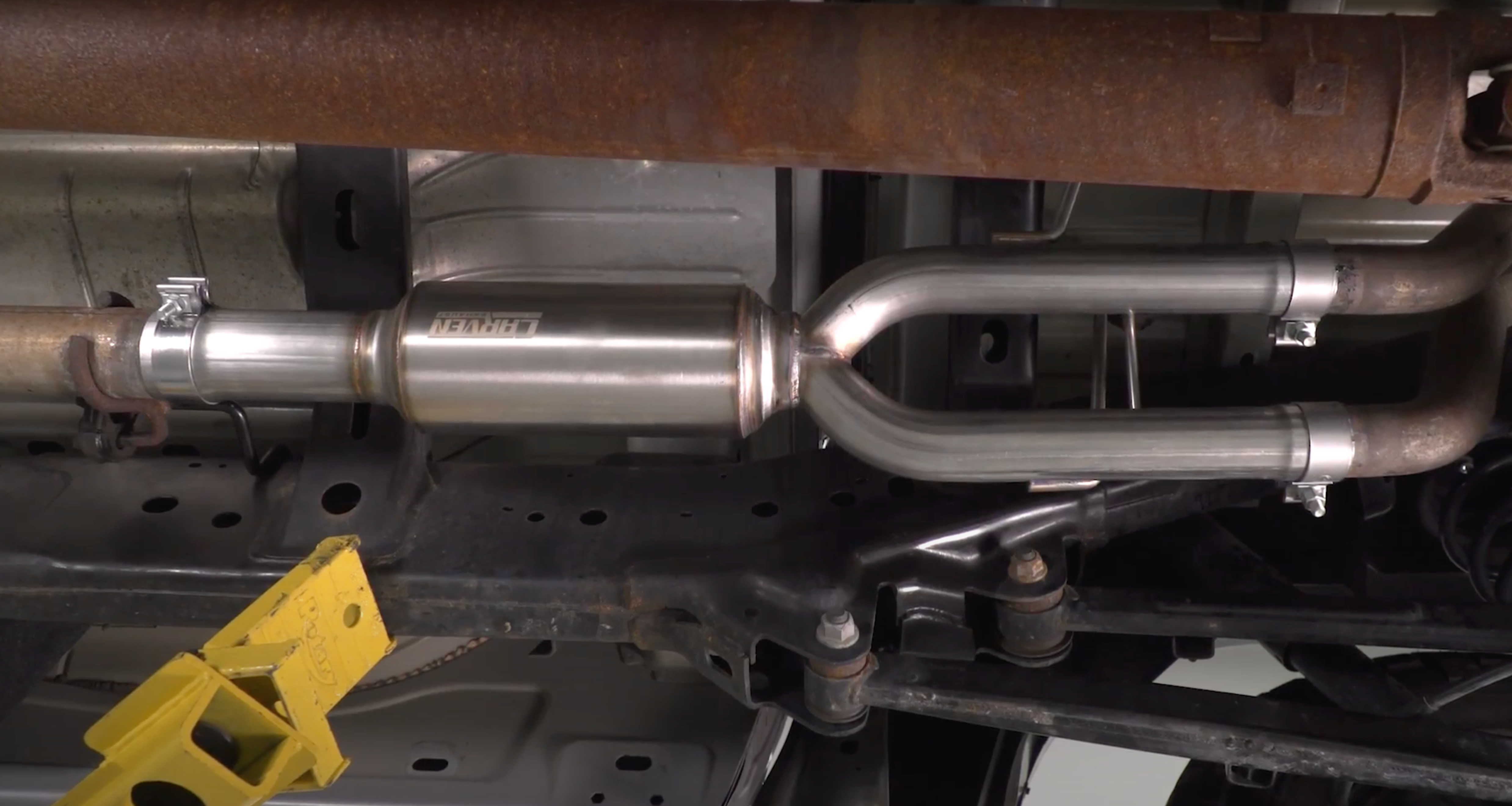 The underside of a vehicle with an installed 2009-2018 RAM 1500 Carven Exhaust Direct Fit Muffler Replacement Kit 