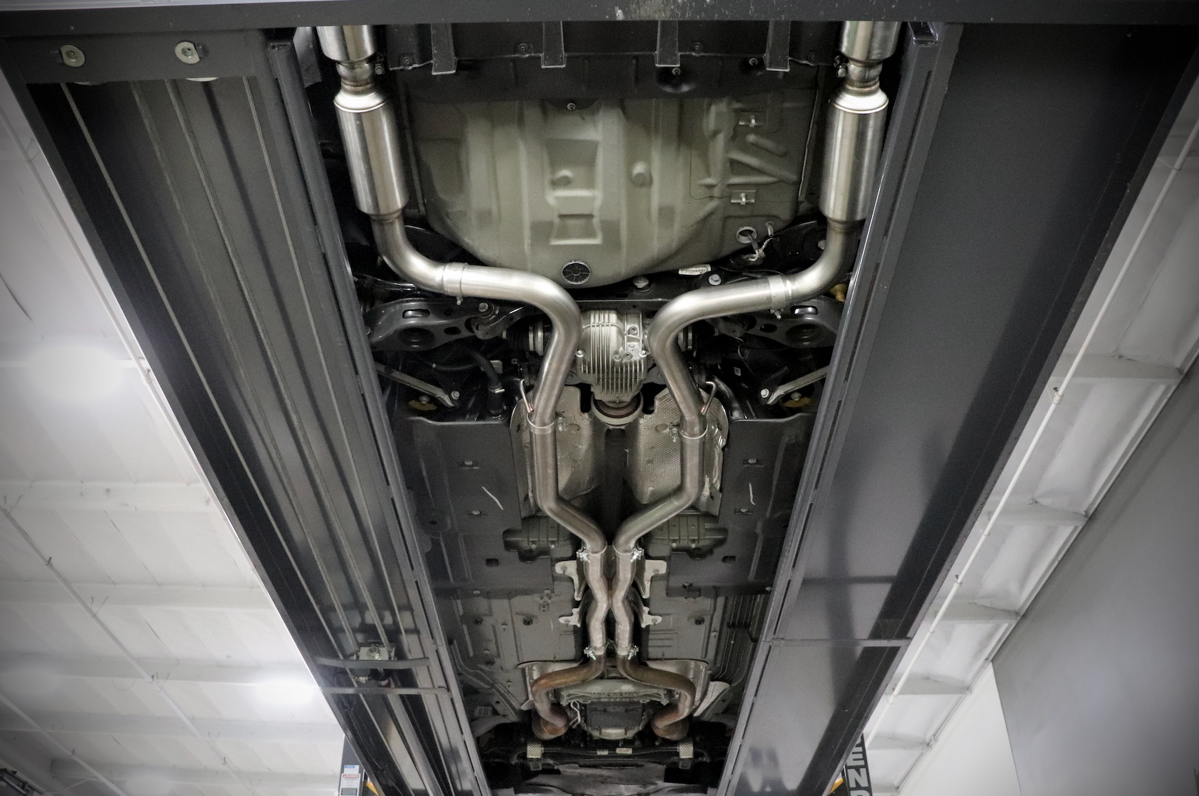 The underside of a vehicle with an installed 2015-2023 Dodge Charger Carven Exhaust Cat-Back Exhaust Kit